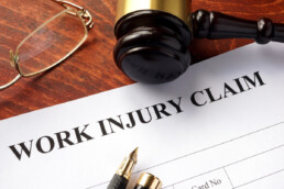 work injury claim form on desk next to gavel, glasses, and pen