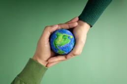 two hands holding globe green